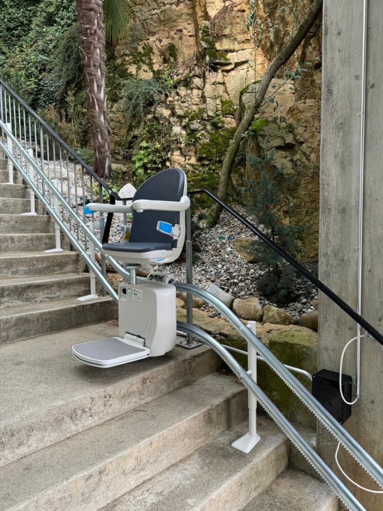 LSM Mobility Siège monte-escaliers installé sur un escalier extérieur à Morges, offrant une solution d'accessibilité avec un cadre rocheux en arrière-plan.