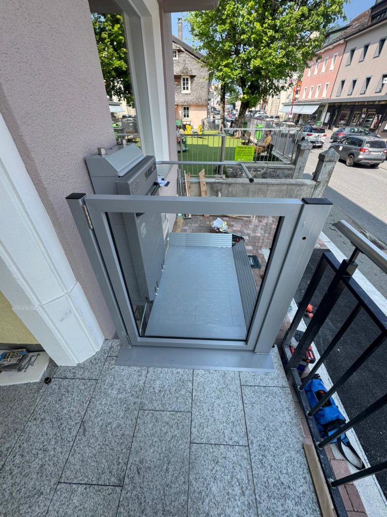 LSM Mobility Plateforme élévatrice Ascendor PLV9 installée sur un balcon, offrant accessibilité dans un cadre urbain pittoresque. Vue plongeante sur la rue animée.