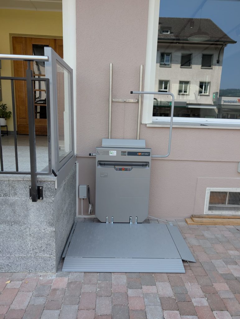 LSM Mobility Plateforme élévatrice Ascendor PLV9 grise installée à l'extérieur d'un bâtiment résidentiel pour l'accessibilité aux personnes à mobilité réduite.