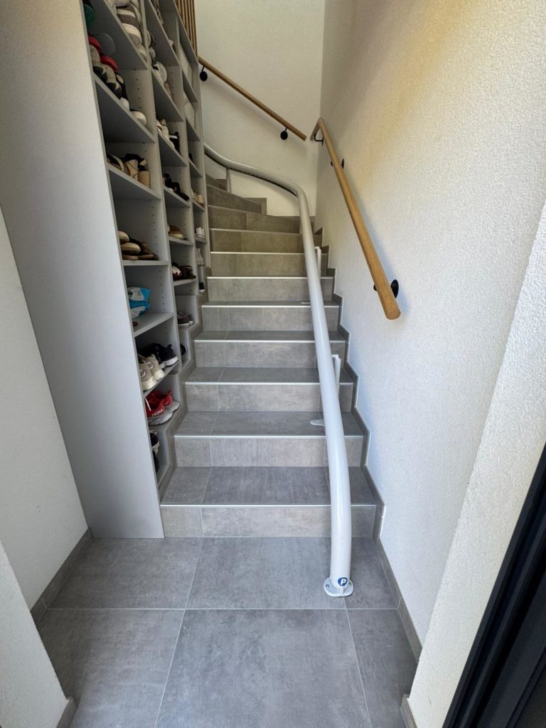LSM Mobility Escalier moderne gris clair avec monte-escalier et étagère à chaussures intégrée. Design d'intérieur optimisé pour l'accessibilité et le rangement.