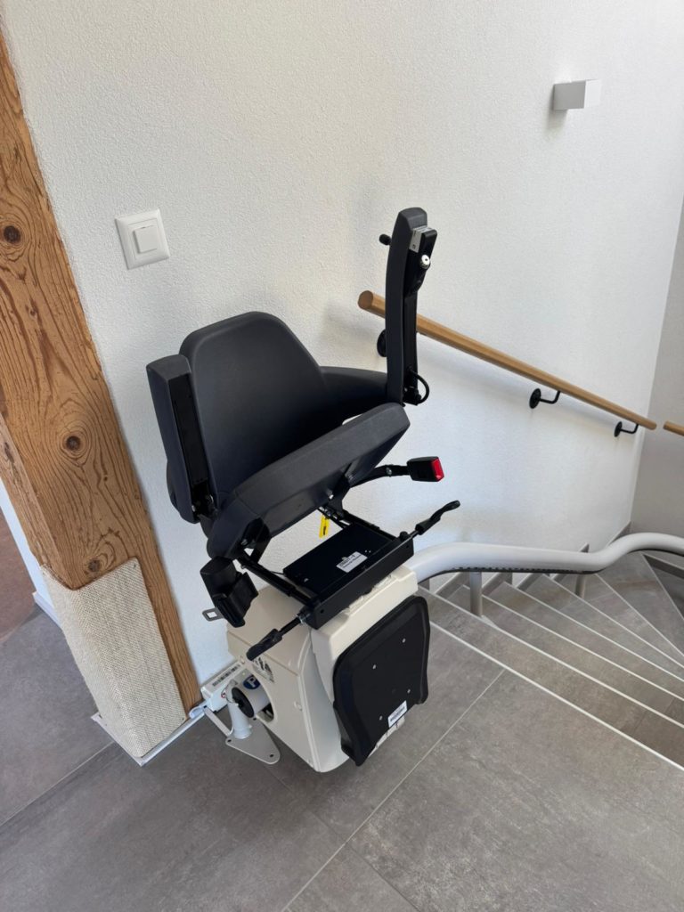 LSM Mobility Monte-escalier moderne installé dans une maison, avec siège noir et rail blanc suivant un escalier carrelé. Solution d'accessibilité pour personnes à mobilité réduite.