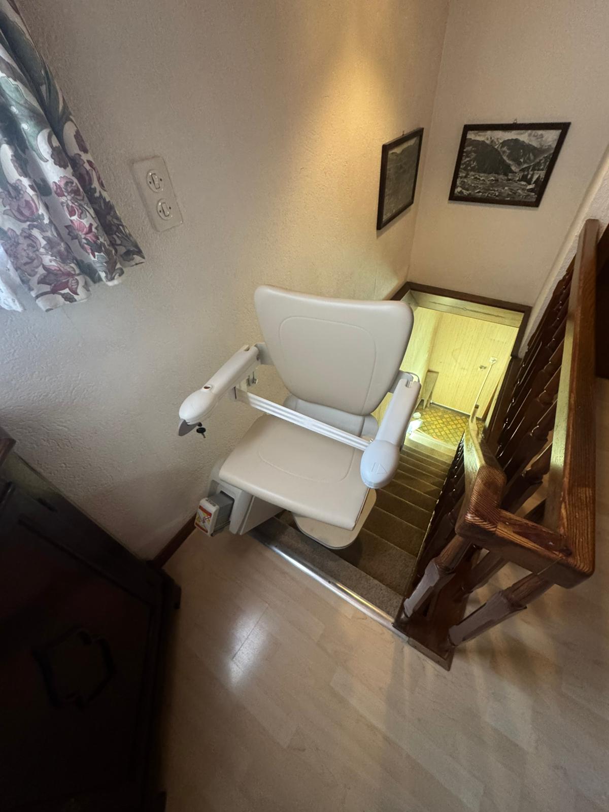 LSM Mobility Monte-escalier beige installé dans un intérieur domestique, offrant une solution d'accessibilité. Détails de la rampe en bois et décorations murales visibles. Solution pour faciliter le quotidien.