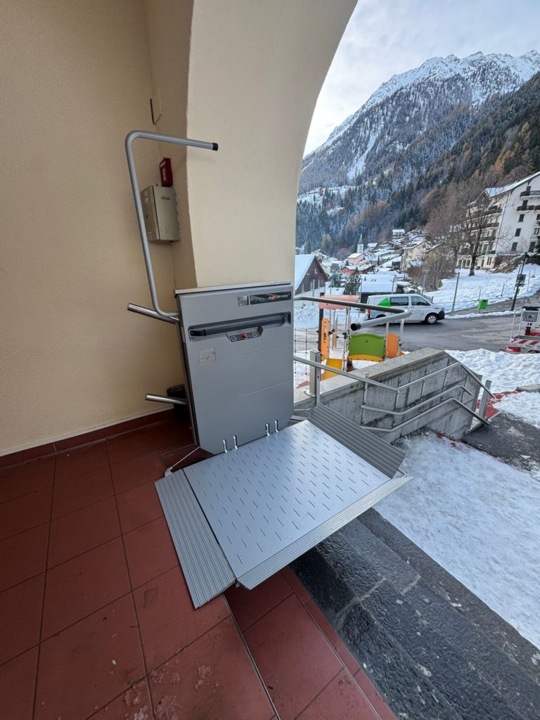 LSM Mobility Plateforme élévatrice installée dans la Vallée du Trient, offrant un accès facilité. Vue sur les montagnes enneigées et le village. "Quick Up" visible sur l'appareil.