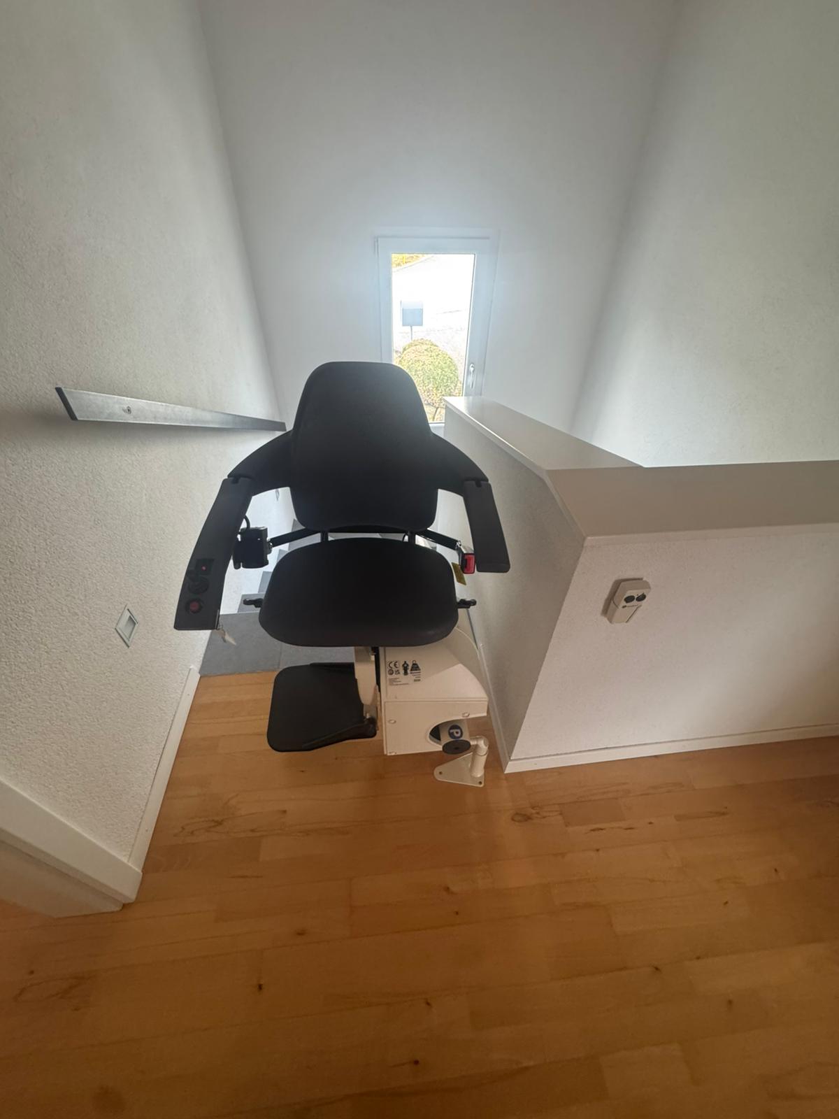 LSM Mobility Un monte-escalier noir installé dans un intérieur clair avec parquet. Solution pour rester chez soi confortablement, offrant mobilité et sécurité.