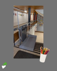 LSM Mobility Ascenseur pour fauteuil roulant installé dans une école pour améliorer l'accessibilité. Plateforme élévatrice grise sur escalier, décorations murales colorées.