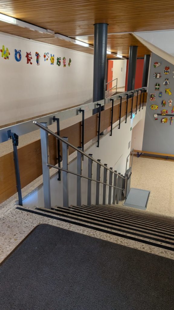 LSM Mobility Escalier d'une école avec rampe d'accès pour personnes à mobilité réduite. Couleurs vives et décorations murales pour un environnement scolaire accessible et accueillant. #AccessibilitéÉcole