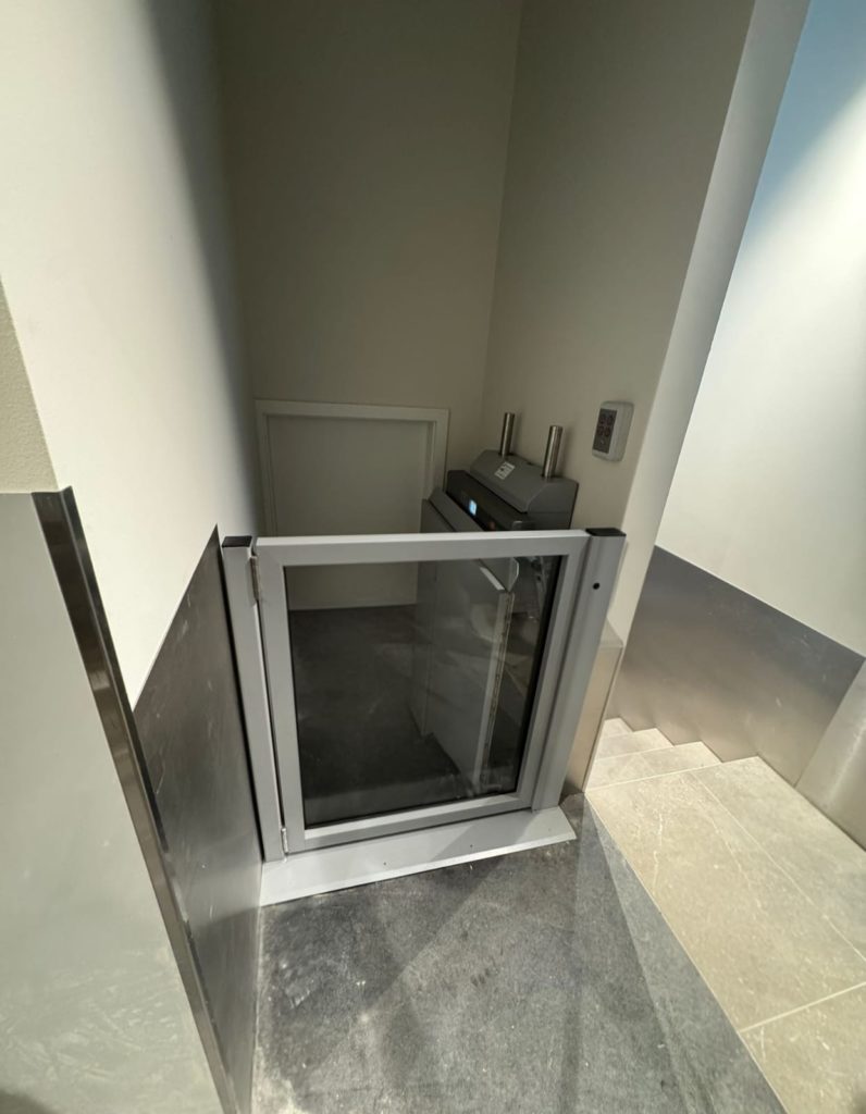 Ascenseur domestique compact avec porte vitrée dans un intérieur moderne. Élévateur pour maison.