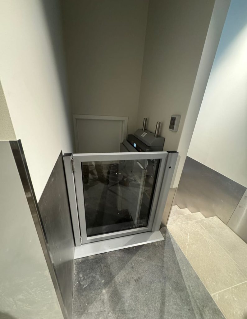 Ascenseur domestique compact avec porte vitrée dans un intérieur moderne. Élévateur pour maison.