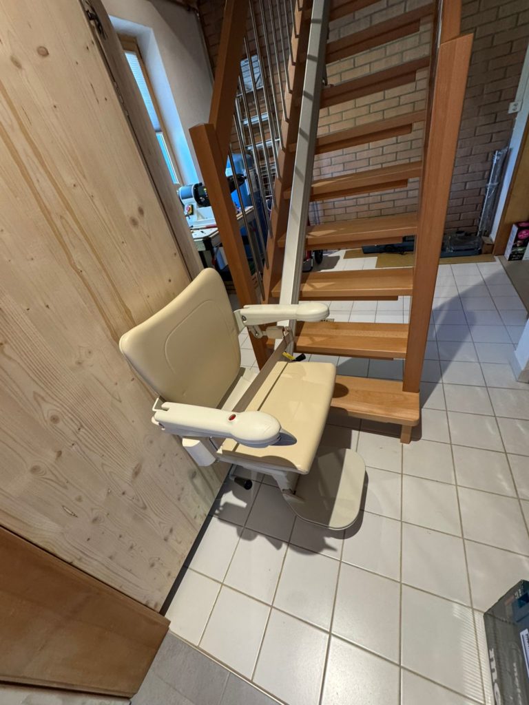 LSM Mobility Siège monte-escalier beige installé sur un escalier en bois.